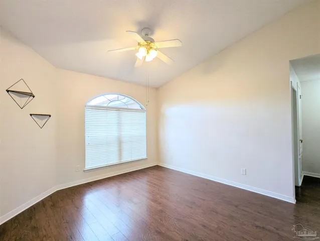 an empty room with wooden floor chandelier fan and windows