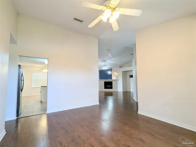 an empty room with wooden floor and ceiling fan