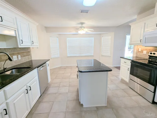 a kitchen with granite countertop a sink a stove top oven and cabinets