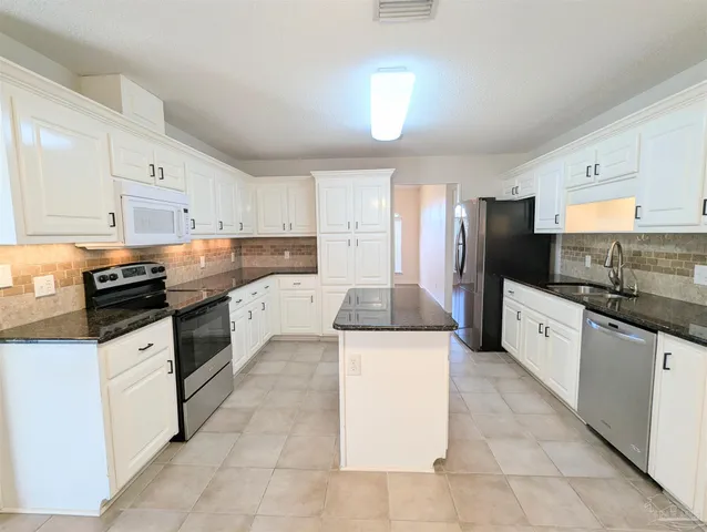 a kitchen with granite countertop a sink a counter top space and cabinets