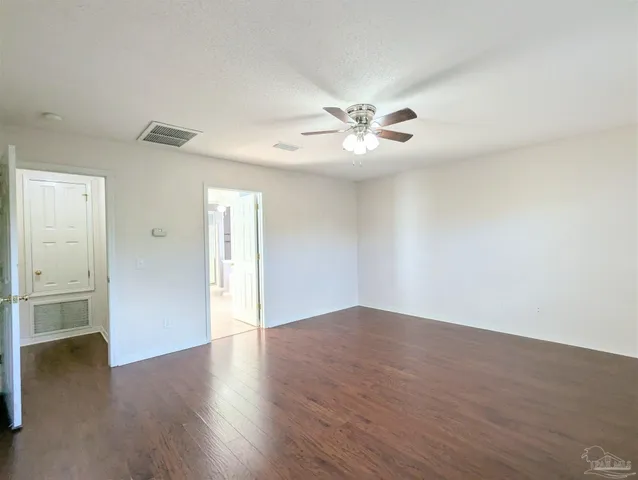 an empty room with wooden floor and ceiling fan