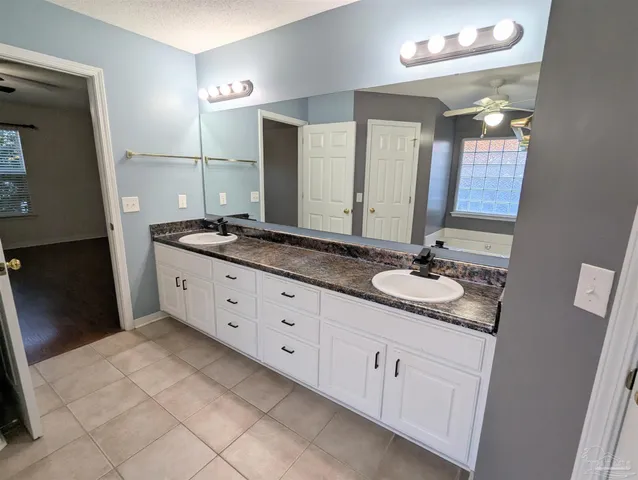 a bathroom with a granite countertop double vanity sink and mirror