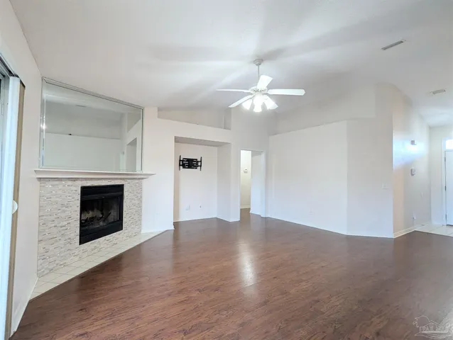 an empty room with wooden floor fireplace and windows