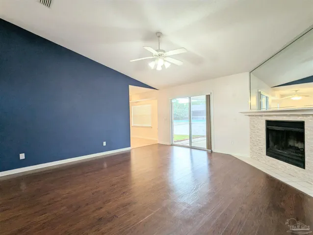 an empty room with wooden floor fireplace and windows