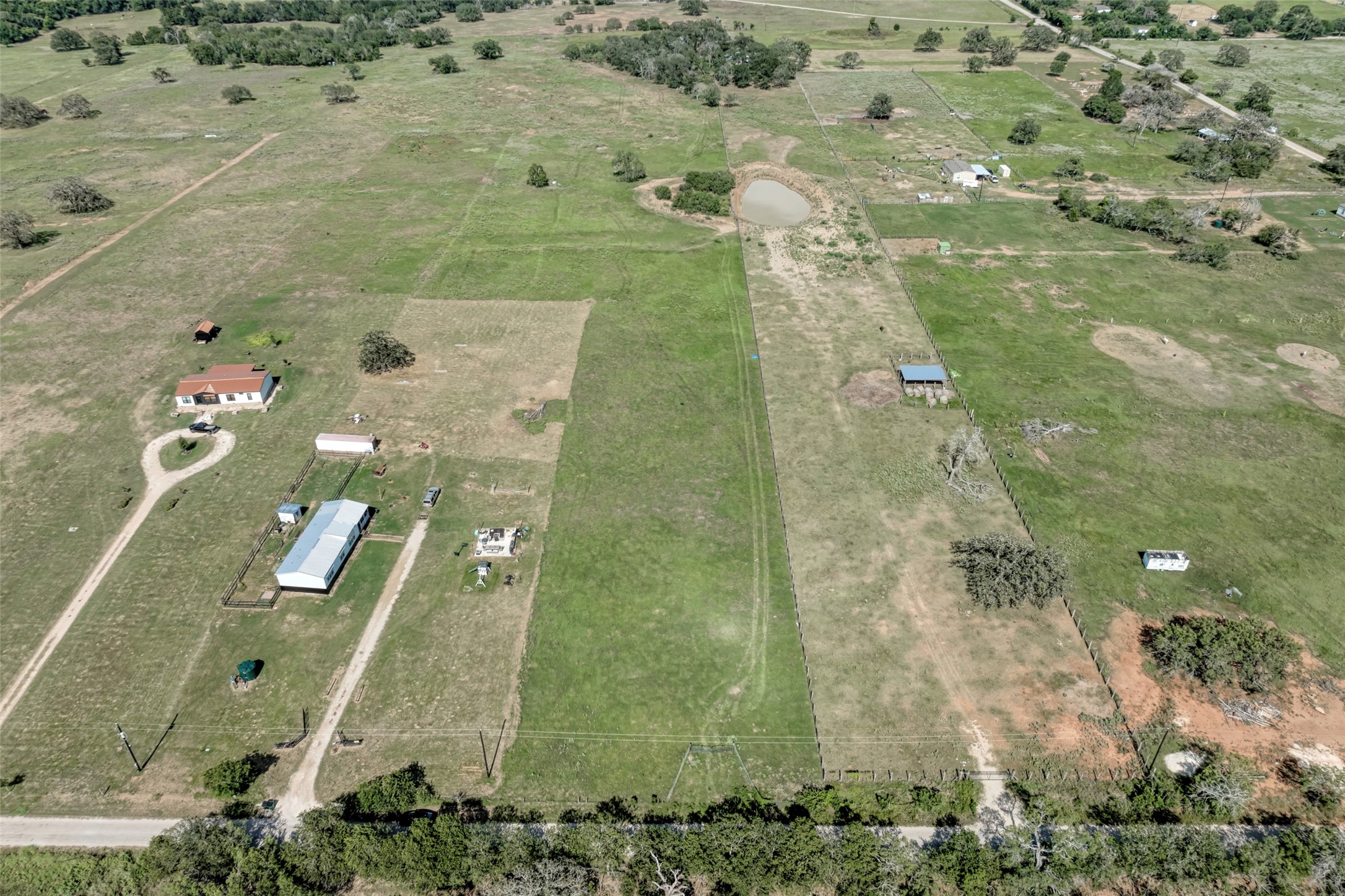 5309 Tenney Creek Road Luling, TX 78648 - Photo 10 of 23 An aerial perspective reveals a vast rural property featuring several structures, expansive green fields, and a tranquil pond.