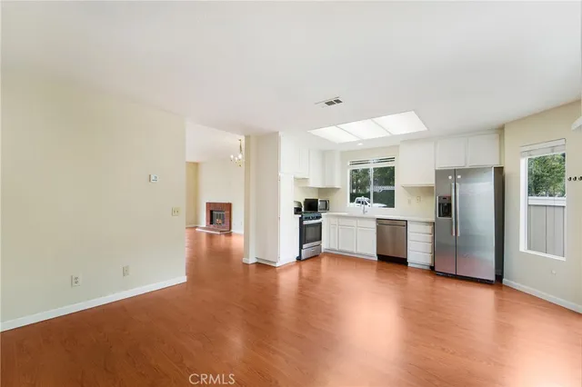 a view of a kitchen with refrigerator and wooden floor