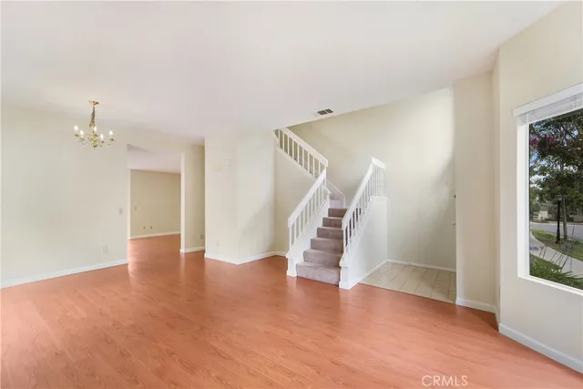 an empty room with wooden floor and staircase