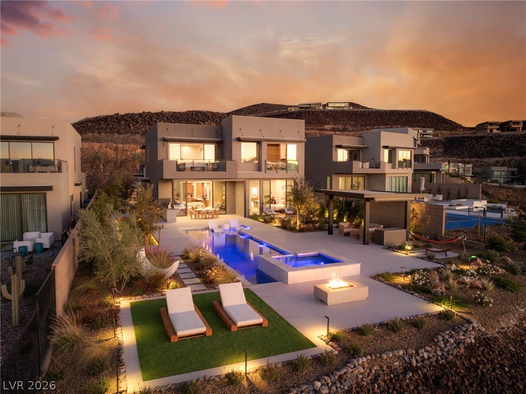 571 Overlook Rim Drive Henderson, NV 89012 - Photo 77 of 85 Back of house at dusk with a patio, a pool with connected hot tub, a balcony, and stucco siding