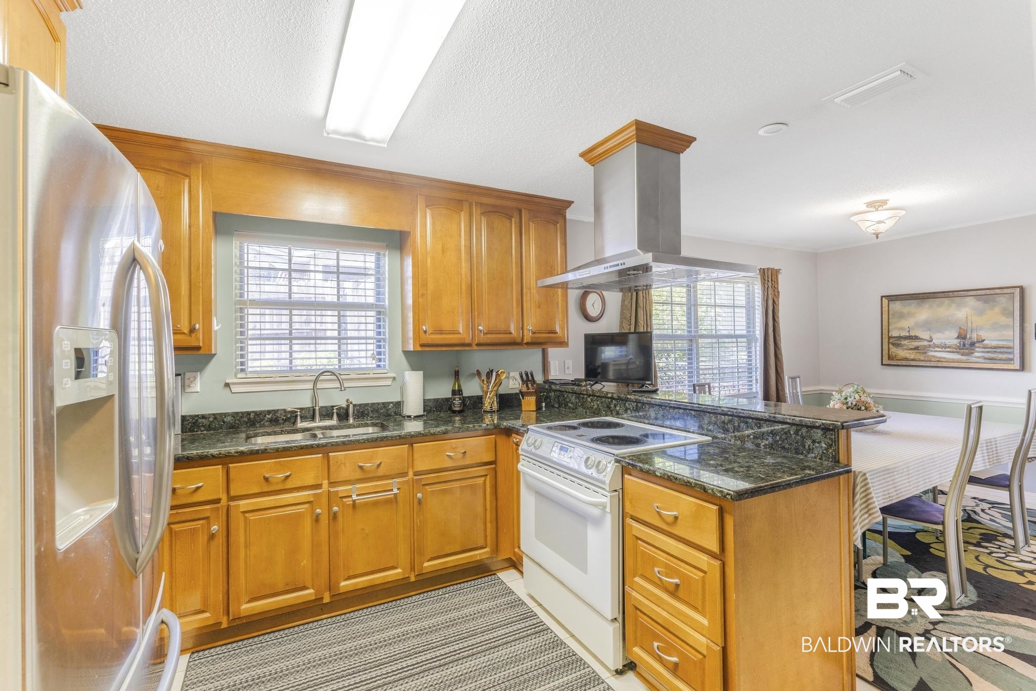 2573 E Road Mobile, AL 36693 - Photo 12 of 45 Kitchen featuring stainless steel fridge with ice dispenser, electric stove, island range hood, brown cabinetry, and dark stone counters
