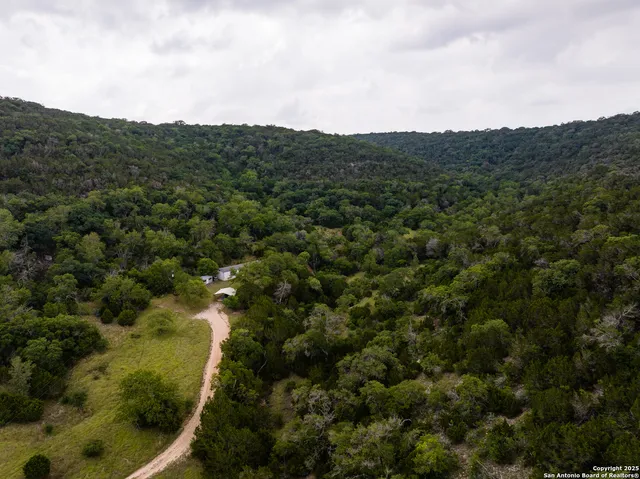 an aerial view of residential houses with outdoor space and trees