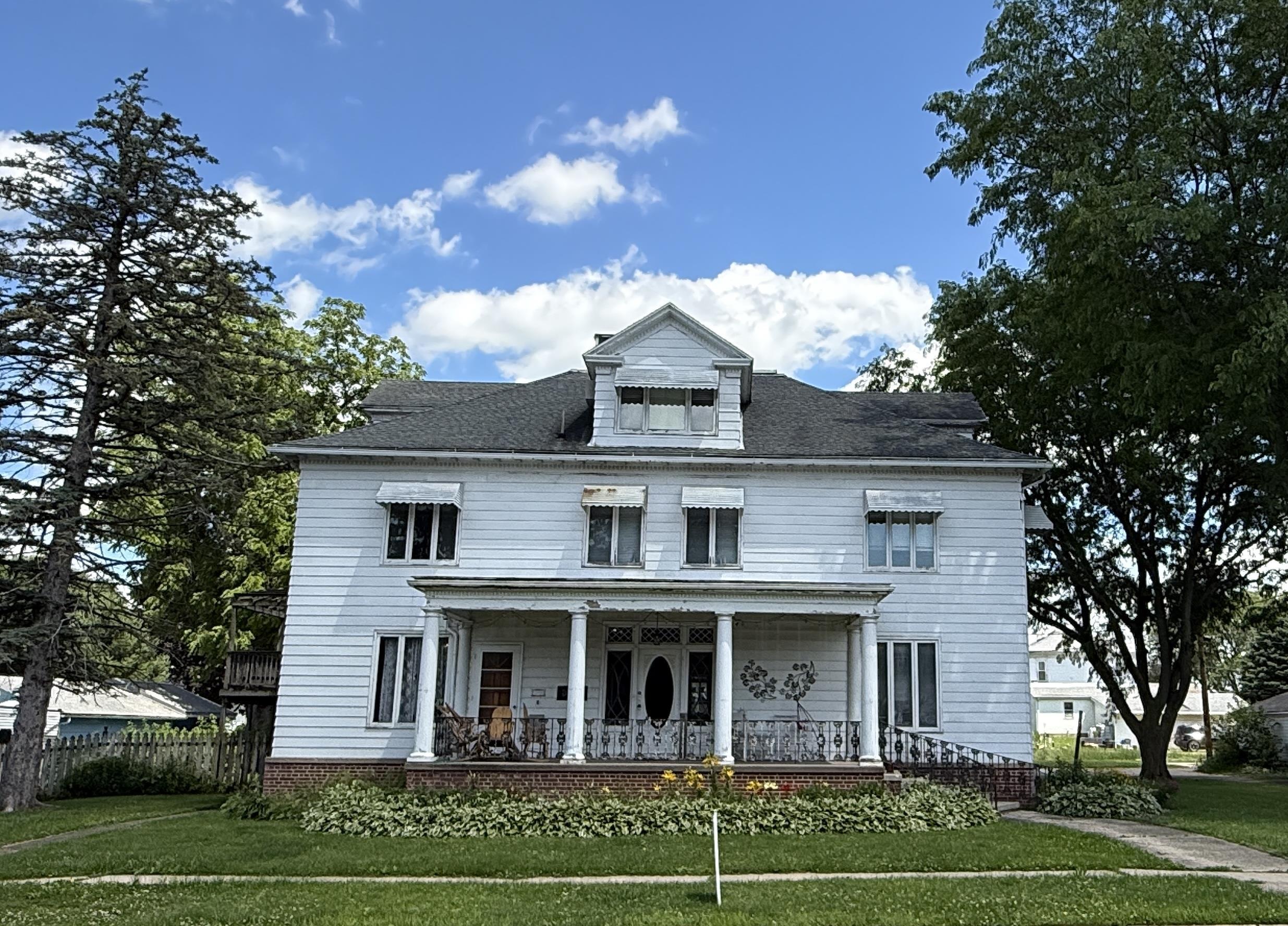 323 South Main Street Stockton, IL 61085 - Photo 2 of 31 a view of a white house with large windows and a large tree