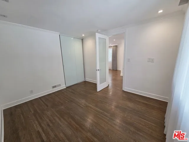 a view of an empty room with wooden floor and closet