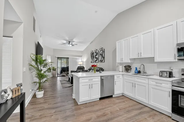 a kitchen with white cabinets and wooden floor