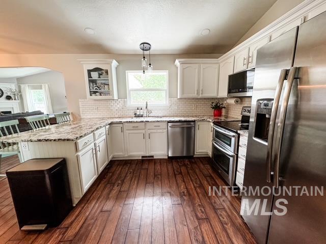 808 O'Leary Way Twin Falls, ID 83301 - Photo 13 of 37 Kitchen featuring wood-finish flooring, white cabinetry, a subway tile backsplash, and stainless steel appliances including a refrigerator, dishwasher, and double oven range