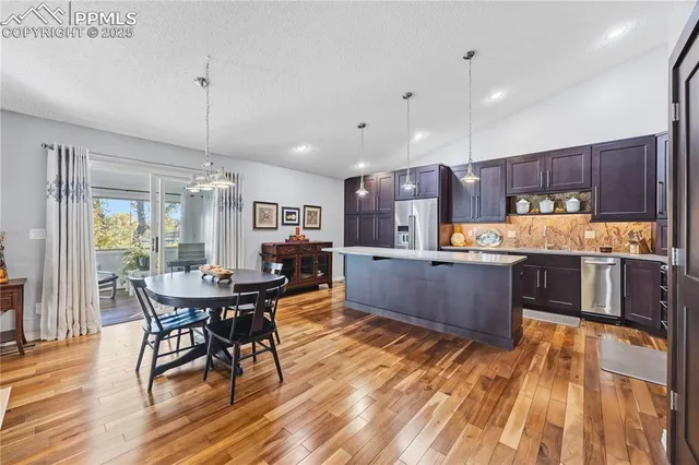 a kitchen with stainless steel appliances kitchen island granite countertop wooden floors and wooden cabinets