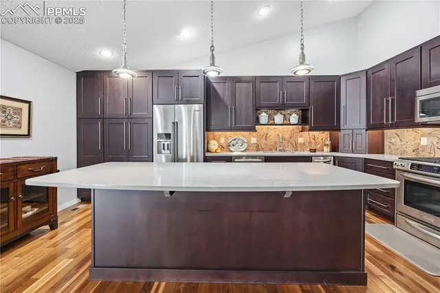a kitchen with kitchen island a counter top space a sink stainless steel appliances and cabinets