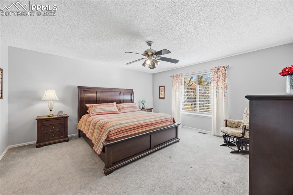 2135 Glenhill Road Colorado Springs, CO 80906 - Photo 19 of 50 a spacious bedroom with a bed and a ceiling fan