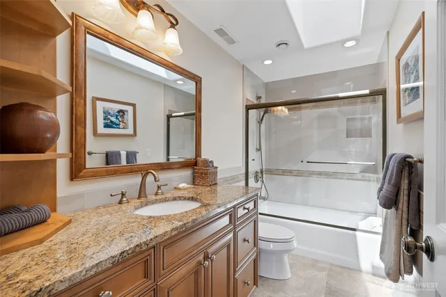 a bathroom with a granite countertop sink toilet and shower