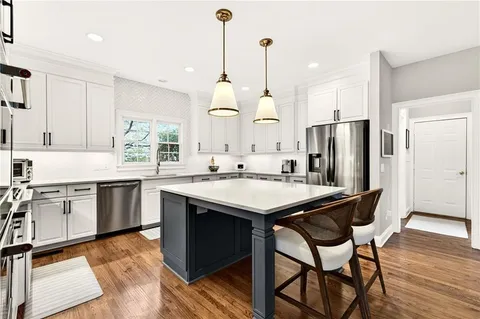 a kitchen with stainless steel appliances granite countertop a table chairs stove and sink