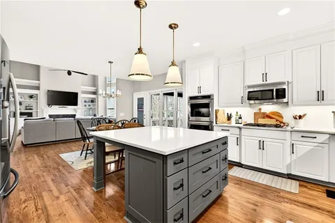 a open kitchen with stainless steel appliances kitchen island a white cabinets and couches