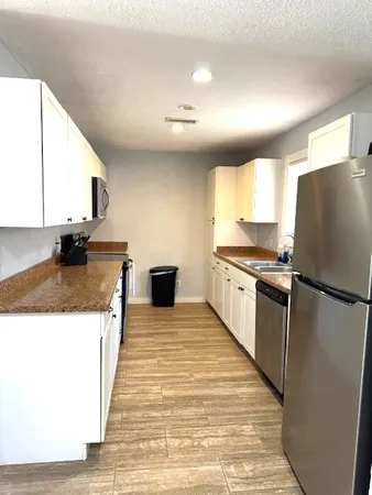 a kitchen with granite countertop a refrigerator and a stove top oven