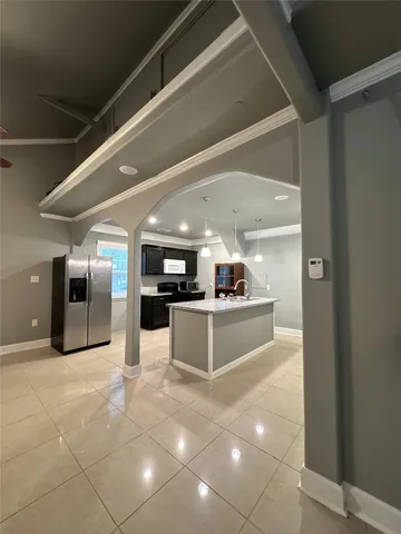 a large white kitchen with stainless steel appliances a large counter top and a refrigerator