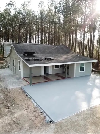 a view of a house with a yard and trees in the background