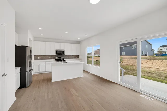 a kitchen with a refrigerator and white cabinets
