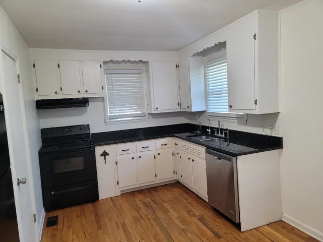 a kitchen with granite countertop white cabinets and black appliances