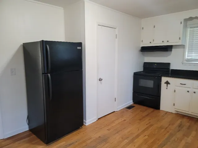 a kitchen with white cabinets and black appliances