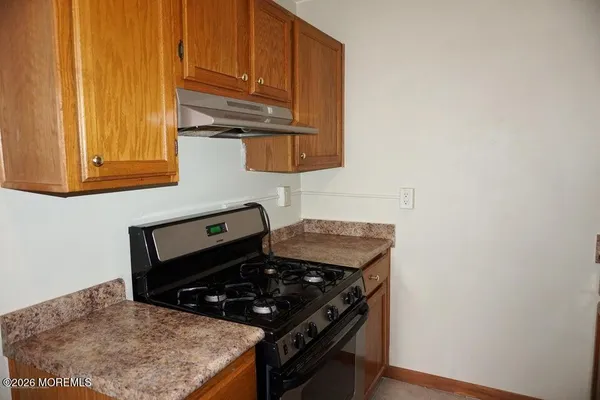 a kitchen with stainless steel appliances granite countertop white cabinets and a stove top oven