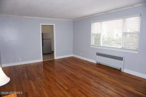 a view of an empty room with wooden floor and a window