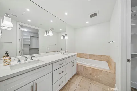 a spacious bathroom with a double vanity sink a mirror and a bathtub