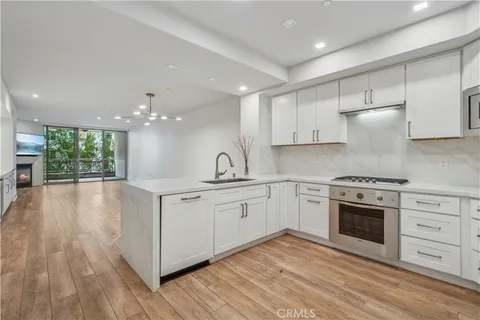 a kitchen with stainless steel appliances granite countertop a stove a sink and white cabinets
