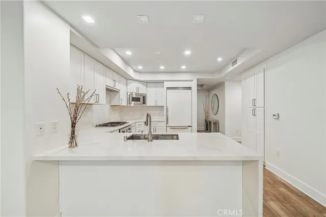 a large white kitchen with kitchen island a sink stainless steel appliances and cabinets