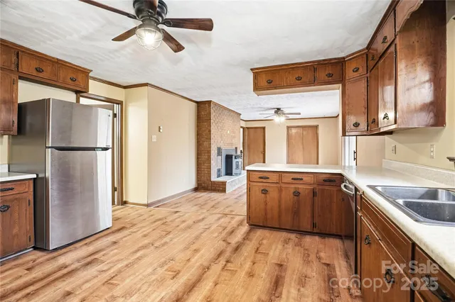 a view of a livingroom with a fireplace a ceiling fan and wooden floor