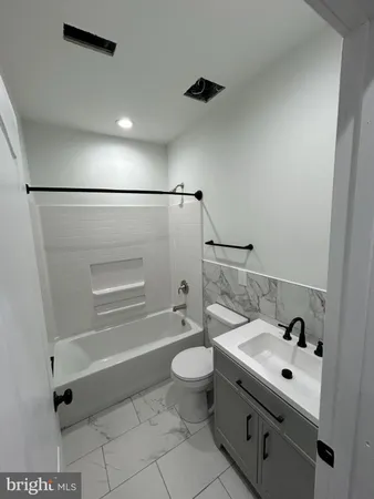 a bathroom with a granite countertop sink a toilet and shower