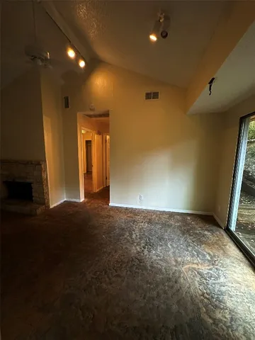 a view of an empty room with wooden floor and a fireplace