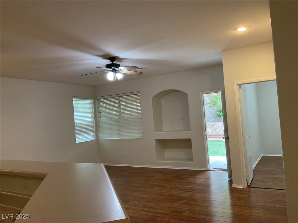 7620 Donald Nelson Avenue Las Vegas, NV 89131 - Photo 14 of 34 Unfurnished living room with dark wood-type flooring, a ceiling fan, built in shelves, baseboards, and recessed lighting