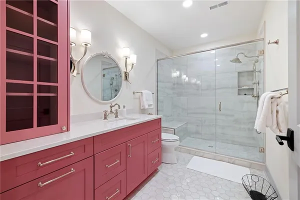 a bathroom with a double vanity sink a toilet a mirror and shower