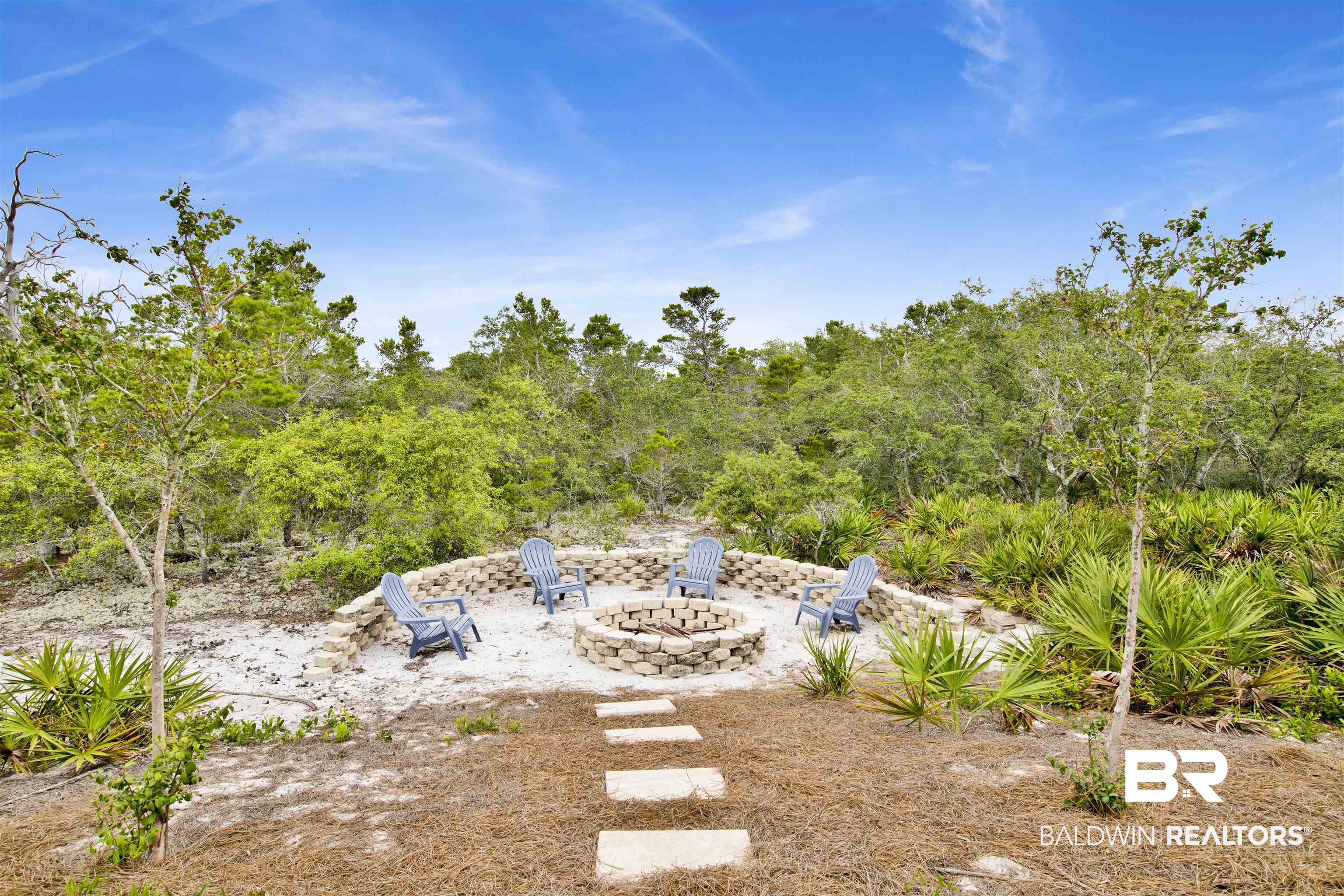 30351 River Road Orange Beach, AL 36561 - Photo 28 of 44 Outdoor fire pit area featuring a stone block fire pit, a low retaining wall, and a stepping stone path