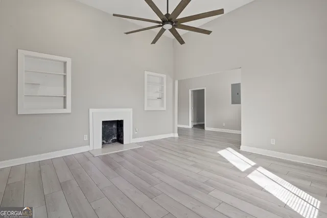 an empty room with wooden floor closet and windows