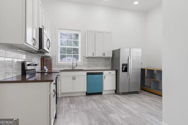 a kitchen with granite countertop white cabinets stainless steel appliances and a sink