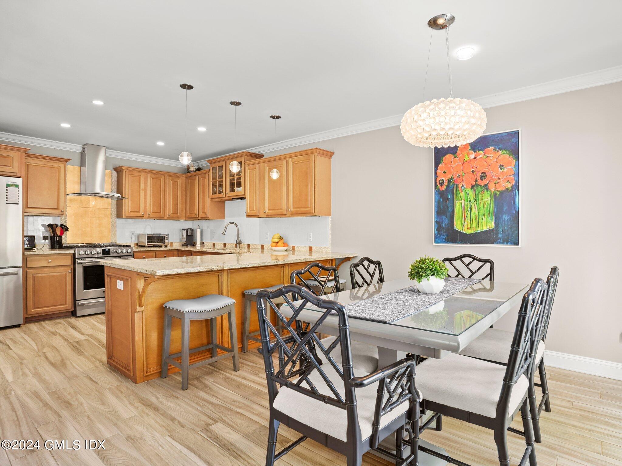 32 Cliff Avenue, Unit 3 Greenwich, CT 06830 - Photo 7 of 23 a kitchen with stainless steel appliances granite countertop a stove top oven a sink a refrigerator and a dining table with wooden floor