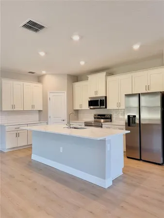 a kitchen with stainless steel appliances granite countertop a stove a sink a refrigerator and white cabinets