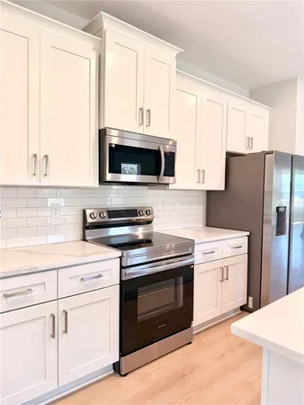 a kitchen with white cabinets and stainless steel appliances