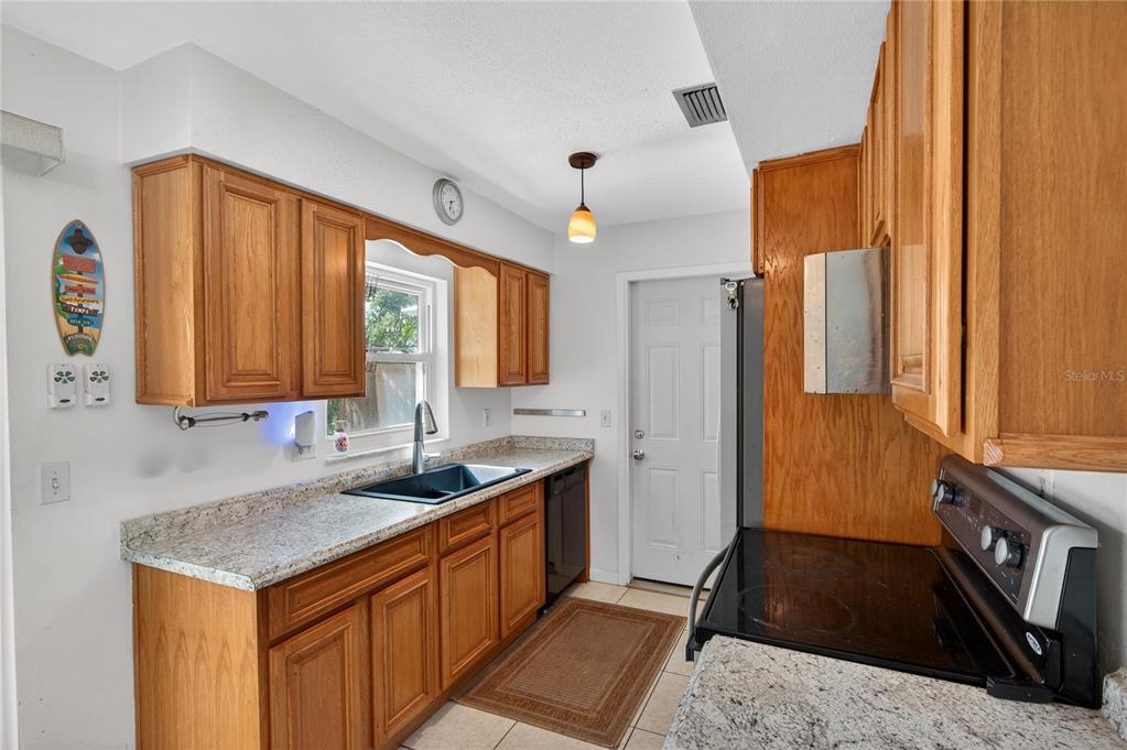 1417 Spring Lane Clearwater, FL 33755 - Photo 9 of 28 a kitchen with granite countertop a sink and a refrigerator