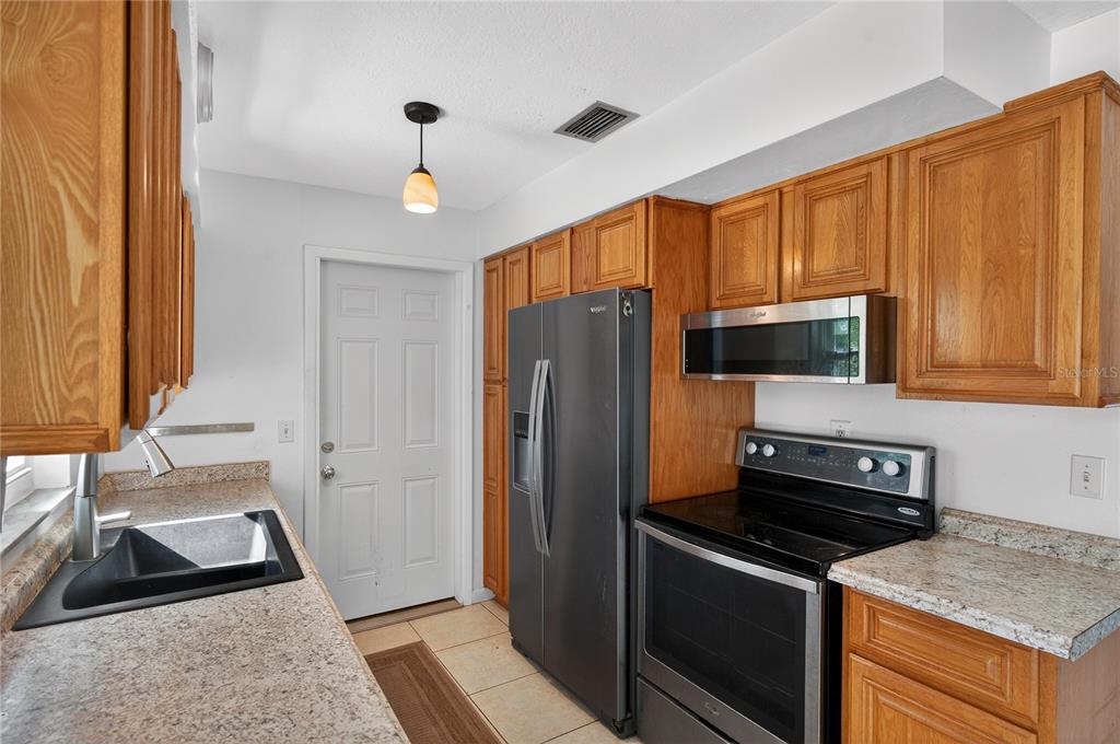 1417 Spring Lane Clearwater, FL 33755 - Photo 10 of 28 a kitchen with granite countertop a refrigerator stove and microwave