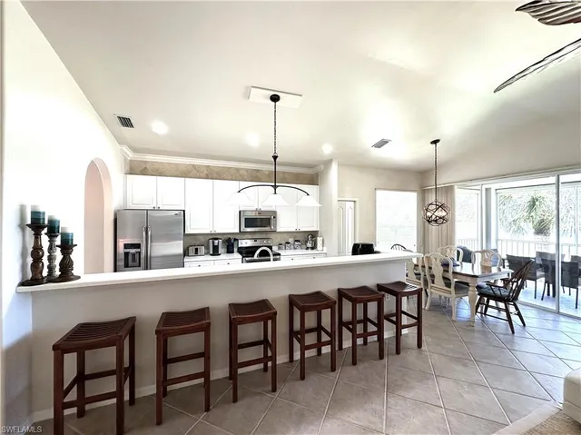 a view of a dining room and livingroom with furniture wooden floor a rug a fireplace and a chandelier
