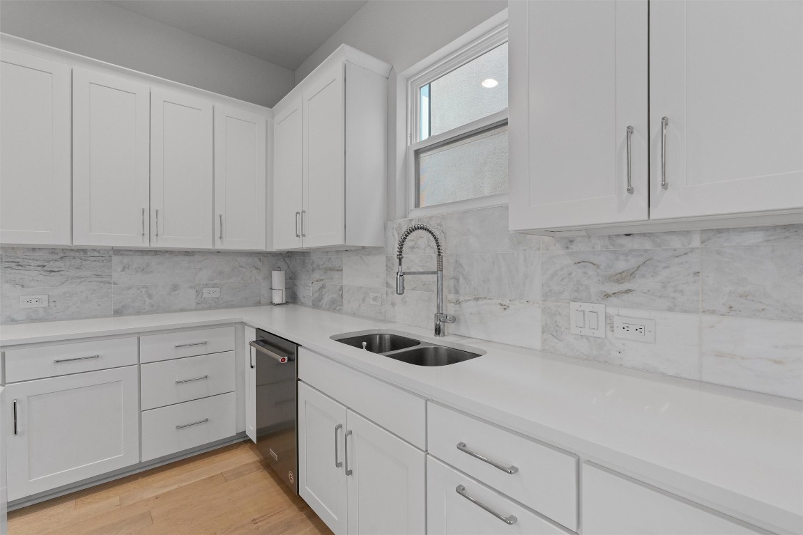 5002 Pecan Springs Road, Unit 1 Austin, TX 78723 - Photo 14 of 38 Kitchen with white cabinets, tasteful backsplash, light stone countertops, light wood-style floors, and stainless steel dishwasher